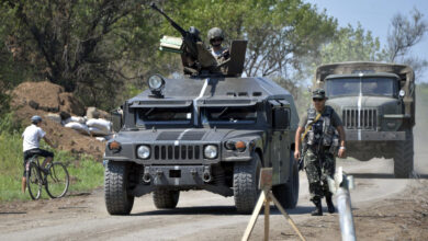 A Ukrainian serviceman walks by an armored personnel carrier in the Donetsk region