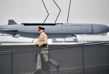 A member of the military walks past an MBDA Storm Shadow/Scalp missile at the Farnborough Airshow, south west of London