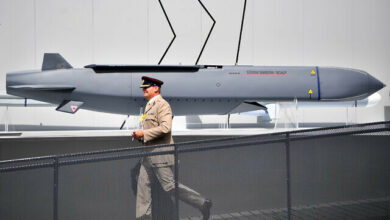 A member of the military walks past an MBDA Storm Shadow/Scalp missile at the Farnborough Airshow, south west of London