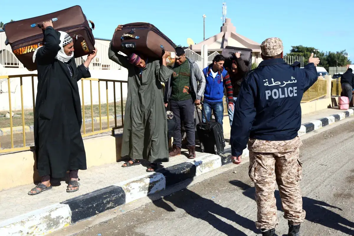 Egyptians walk carrying their belongings in Libya