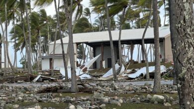 The Roi-Namur church steeple rests on the coral-strewn grounds on the opposite side of the Tradewinds Theater, background, from where it once stood
