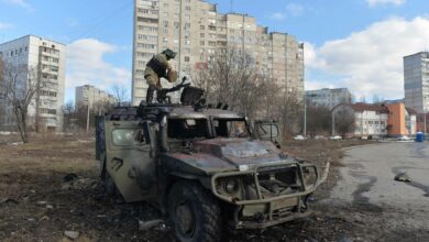 A Ukrainian Territorial Defense fighter examines a destroyed Russian infantry mobility vehicle GAZ Tigr after the fight in Kharkiv