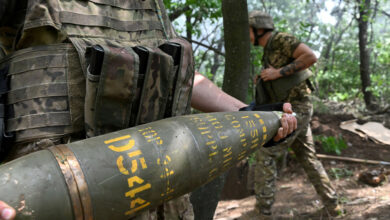 A Ukrainian artilleryman carries a 155 mm shell to fire a M777 howitzer toward Russian positions near Avdiivka in the Donetsk region