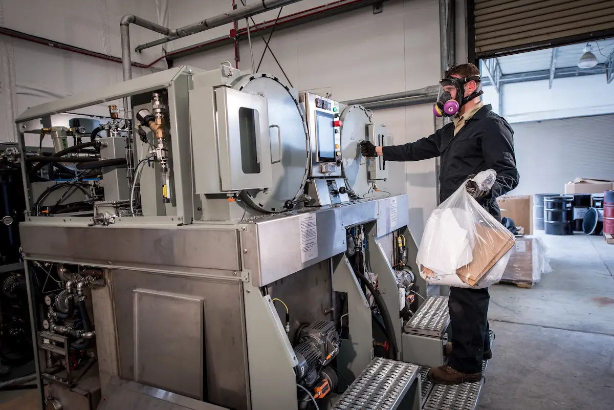 An engineer with the Naval Surface Warfare Center loads the Micro-Auto Gasification System incinerator to thermally destroy solid waste