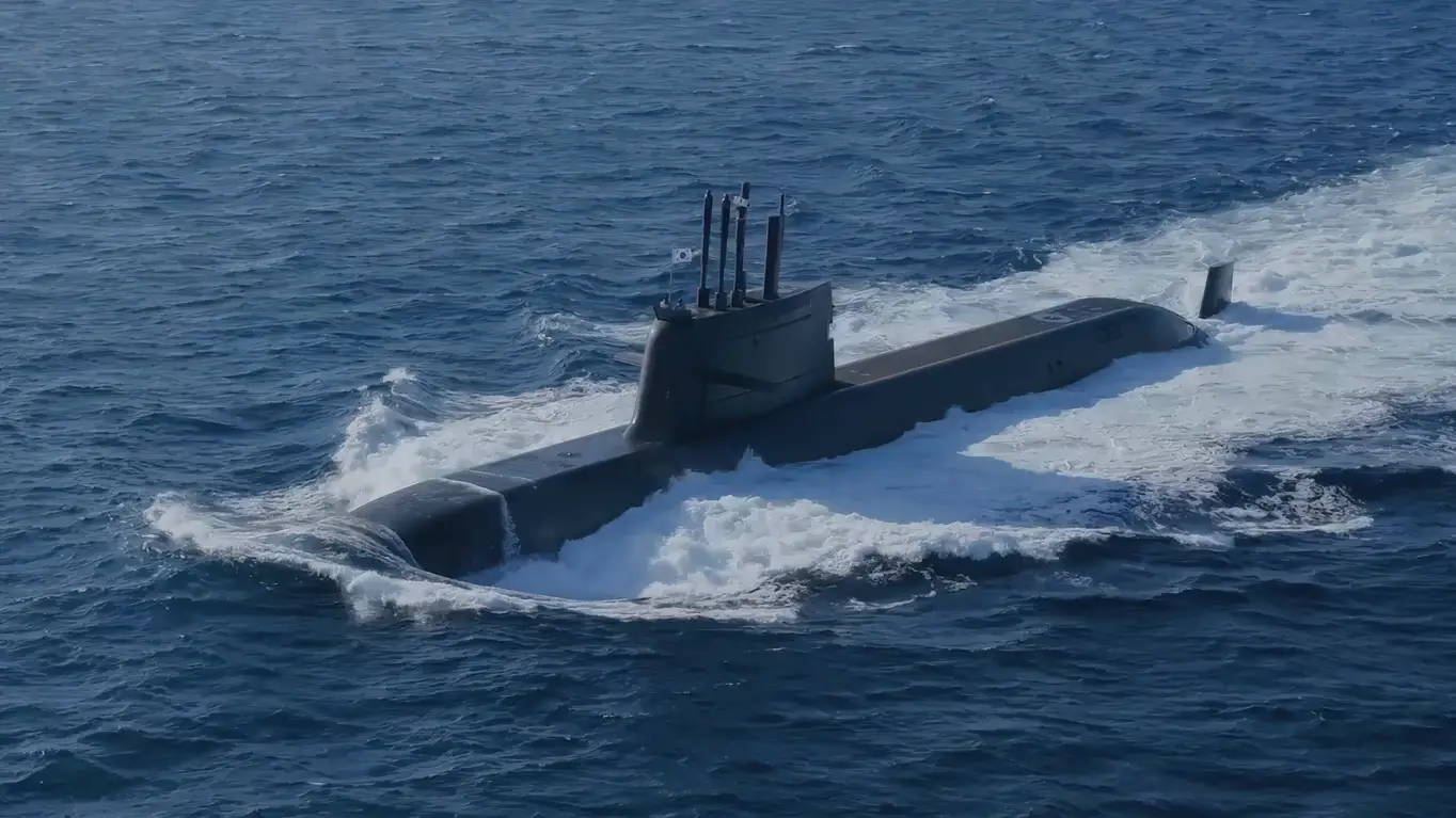 ROKS Dosan Ahn Changho (SS-083), a Jangbogo-III class submarine, is seen floating half-submerged in deep blue waters. The ship is painted black. A South Korean flag is seen hoisted up on a pole on top of the submarine's sail.
