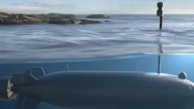 An artist's rendering of an uncrewed combat underwater vehicle. The drone is submerged underwater, while its periscope sticks out the water's surface. A rocky shore is seen over on the left side of the horizon.
