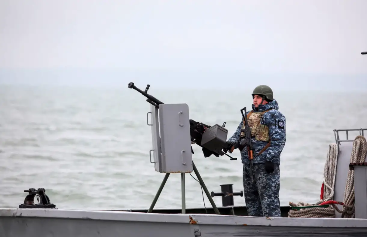 A Ukrainian serviceman standing guard as he boat patrols a water area of Ukraine's Black Sea port of Mariupol